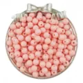 Close-up detail shot of pink acrylic round beads in a silver bow tray for DIY jewelry crafts. - Nude