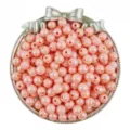 Detailed close-up view of shiny pink acrylic round beads with AB coating in a bow dish. - Orange