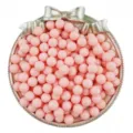 Close-up detail of pink solid round craft beads displayed in a decorative silver bow tray. - Orange