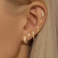 Close-up detail shot of multi-piece gold-plated crystal stud and hoop earrings set on ear. - 6-Piece Earrings Set / 24K / Set of 6 / Gold