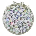 Detail shot of white acrylic smiley face beads in a silver bow tray, DIY jewelry making. - White And Colorful