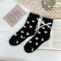 Gros plan détaillé de chaussettes douillettes en polaire avec motifs de cœurs et beau nœud. - Taille unique / Noir