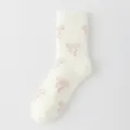 Detalle de calcetines de felpa suave, tierno diseño de lazo rosa, textura mullida y cálida. - No se Desprende / Blanco Roto