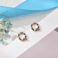 Close-up detail shot of colorful rhinestone letter Q stud earrings, delicate copper jewelry. - Letter Q