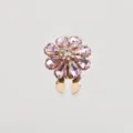 Primo piano sul dettaglio della spilla a fiore con strass rosa e cristalli scintillanti. - Rosa