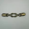 Primo piano della clip per maglione vintage in bronzo con nodo e raffinata struttura. - Rame