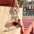 Close-up of a creative wine glass and bottle keychain charm on a woven bag - Wine Glass + Wine Bottle