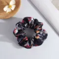 Grand chouchou de Noël en satin noir avec des motifs festifs de cadeaux et de rubans - Noël Noir