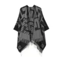 Primo piano dettagliato di mantella in maglia nera e grigia con motivo geometrico e frange. - Grigio nero