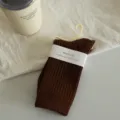 Brown ribbed crew socks with paper band and hanger, stylish and cozy daily wear option. - Caramel color