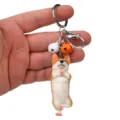 Nahaufnahme des niedlichen Yoga Corgi Anhängers mit Schlüsselring und bunten kleinen Glocken. - Einbeiniger Yoga-Corgi / Weiß-Orange