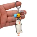 Detailansicht des niedlichen Yoga-Hund-Schlüsselanhängers mit Glocken und stabilem Metallverschluss. - Einbeiniger Stand Husky / Gelb Blau