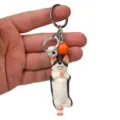 Nahaufnahme des süßen Yoga-Hund-Schlüsselanhängers mit Metallring und bunten Glocken. - Einbeiniger Stand Husky / Weiß-Orange