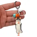 Niedlicher Yoga-Hund Schlüsselanhänger mit bunten Glocken und Karabiner, Detailansicht. - Einbeiniger Stand Husky / Orange und Hellblau