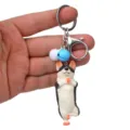 Nahaufnahme des witzigen Yoga-Hund Schlüsselanhängers mit Glöckchen und Karabinerhaken. - Einbeiniger Stand Husky / Blau Weiß