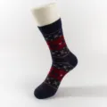 Close-up detail of Christmas knitted mid-tube sock featuring retro elk and snowflake pattern. - Black