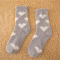 Vista dettagliata di accoglienti calze morbide grigie con cuori bianchi, tessuto peluche. - Taglia 35-40 / Grigio