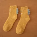 Nahaufnahme von kuscheligen gelben Wintersocken mit niedlichen 3D-Dinosaurier-Stacheln, weich. - Größe 35-40 / Gelb