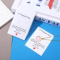 Λεπτομερης οψη του κολιε με καρδια και σετ καρτων ευχων με ζεστο μηνημα αγαπης και αγκαλιας. - Λευκό χαρτόνι Pocket Hug / 7x9cm