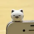 Cute white cat phone dust plug detail shot, anti-dust plug accessory for mobile phones. - White