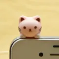 Cute pink cat phone dust plug detail shot, adorable cartoon kitty accessory for smartphone users. - Pink