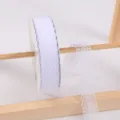 White lace ribbon roll on wooden display stand for gift wrapping and craft decoration. - White
