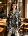 Vista dettagliata di mantella in maglia chevron nera e bianca con frange in un caldo caffè. - Scialle con Nappe Chevron / Nappine bianche