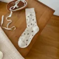Detailopname van zoete geborduurde sokken, gezellige gebreide textuur op houten achtergrond. - Havermout kleine roos / Havermoutkleur