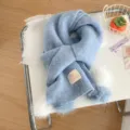 Primer plano de la bufanda de invierno azul claro acogedora con pompones y etiqueta. - Azul