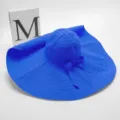 Detail van de blauwe zonnehoed met brede rand, geplooide kroon en schattig strikje voor zomer. - 20 cm brede rand parapluhoed - koningsblauw