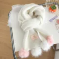 White knitted winter scarf with cute pom pom details, cozy winter accessory detail shot. - White