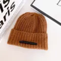 Braune Strickmütze Detailansicht mit weicher Wolle Textur und einzigartigem Mode Buchstabenetikett. - Kaffeebraun