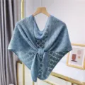 Close-up detail of the light blue knitted hollow shawl scarf hanging neatly on display. - Blue