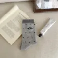 Calzini grigi da donna con graziosi pois neri e un elegante ricamo a forma di fiocco. - Grigio chiaro