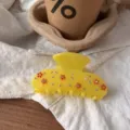 Nahaufnahme Detail der transparenten gelben Harz Haarklammer mit bunten Strasssteinen und Blumen. - Strass Blume Stil / Gelb