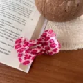 Close up detail of a cute pink leopard print bone shaped hair clip on a book surface. - Rose Pink Speckled