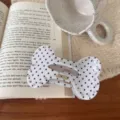 Detailaufnahme einer knochenförmigen Haarklammer mit schwarzen Punkten und funkelnden Strasssteinen. - Strass Knochen Lazy Klammer / Weiß Punktmuster