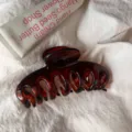 Close-up detail of dark brown hair claw clip, hollow design, elegant minimalist hair accessory. - Round Head Dragon Bone / Large Style / Glossy Tortoiseshell