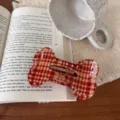 Detailed view of red plaid bone-shaped hair claw clip with sparkling rhinestones, elegant. - Rhinestone Bone Lazy Clip / Vintage Red Plaid