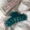 Detail view of a dark teal resin hair claw clip with hollow keel design on white fabric. - Round Head Dragon Bone / Large Style / Dark Cyan