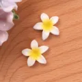 Detalle de primer plano de cabujones de flores de resina de frangipani blanco y amarillo. - Blanco