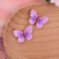 Detailed view of glossy purple gradient butterfly resin flatbacks for DIY phone cases and bows. - Purple