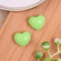 Primer plano de cabujones de resina en corazón verde claro brillante sobre madera para manualidades. - Verde