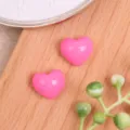 Primer plano de dijes artesanales de corazones de resina rosa brillante sobre madera. - Rosa Oscuro