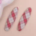 Close-up detail of red and white plaid oval fabric patch craft accessory for DIY decoration. - Red