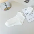 Nahaufnahme von weißen Baumwoll-Mittelsocken mit feiner Stricktextur und Rippbündchen. - Milchweiß