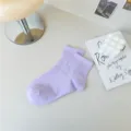 Nahaufnahme Detail von weichen pastelllila Baumwollsocken, gemütliches Schreibtisch-Setup. - Lila