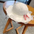 Detailed view of cute baby white fisherman hat with lace mesh ruffle, pearls and plaid bow. - 54cm / Off White