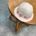 White floral embroidered bucket hat close-up, featuring adjustable chin strap for kids. - Beige Lace Bows
