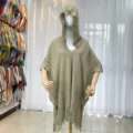 Close-up detail of knitted hooded poncho with fringe trim and wooden button closure design. - Army Green